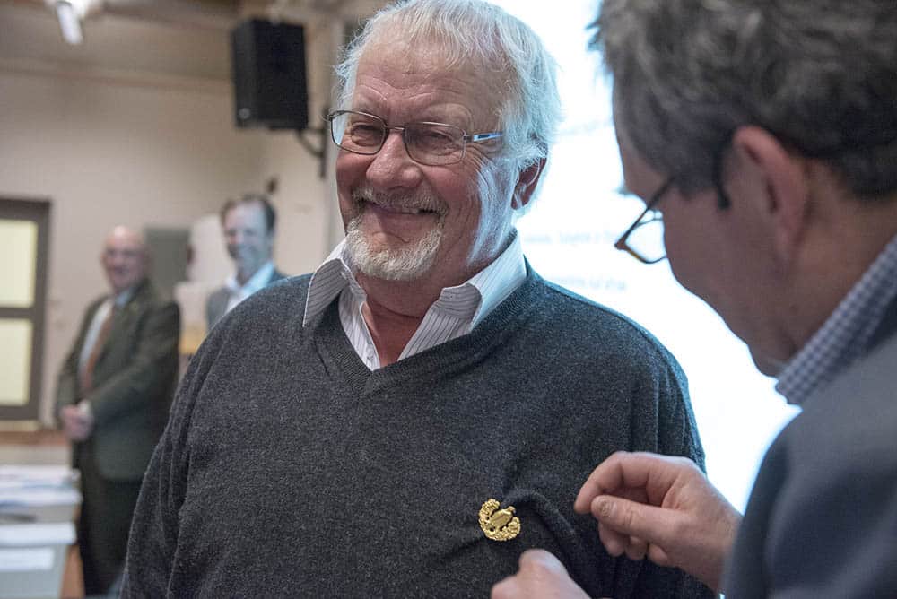 Allan Andersson, Aneby, var påtagligt berörd när han belönades med Svenska Jägareförbundets förtjänstmedalj i guld för sitt arbete i Jönköpings länsförening. Ordförande Gunnar Lindblad fäster utmärkelsen. Foto: Jan Henricson