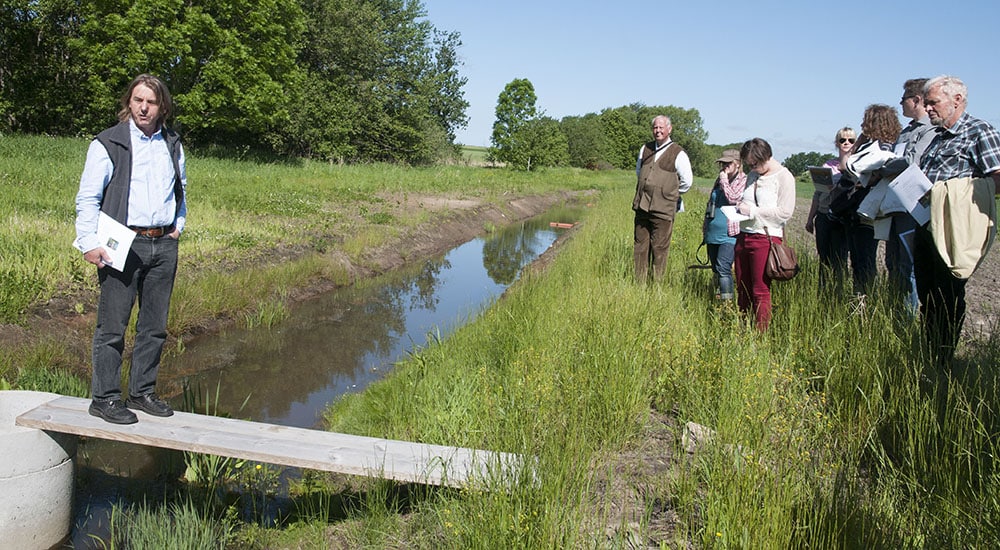 Årets våtmarksstipendiat Peter Feuerbach är en nytänkare. Vid Hushållningssällskapets anläggning söder om Halmstad utvecklar han nya metoder för att använda våtmarker som naturens eget reningsverk. Lyssnar gör Våtmarksfondens ordförande Lars Ingelmark, längst till vänster av åhörarna. Foto: Jan Henricson